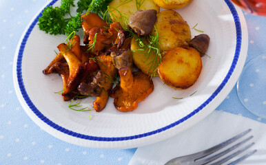 Fried chanterelles with baked potatoes and chicken hearts garnished with fresh greens