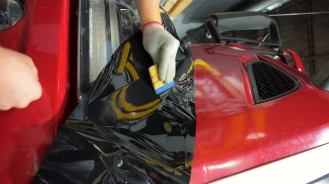 Process of applying a PPF film with a scraper to a truck. Close up footage of applying a film on a car. 
