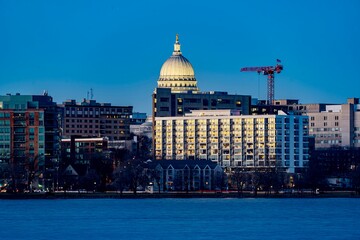 Obraz premium Downtown Madison, WI and the Wisconsin State Capitol Building behind Lake Monona at Twilight