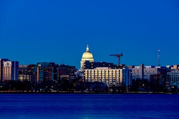 Obraz premium Downtown Madison, WI and the Wisconsin State Capitol Building behind Lake Monona at Twilight