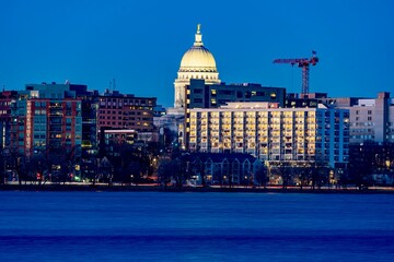 Obraz premium Downtown Madison, WI and the Wisconsin State Capitol Building behind Lake Monona at Twilight