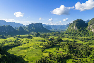 Obraz premium Aerial view of a lush green valley surrounded by towering mountains under a clear blue sky