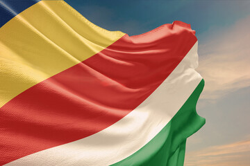 Waving flag of Seychelles in blue sky. Seychelles flag on pole for Independence Day. The symbol of the state on wavy fabric.
