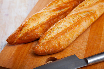 Closeup of two long thin French loaves on wooden surface. Fresh baked goods