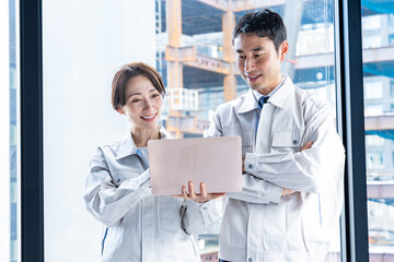 工事現場をバックにパソコンを見る男女