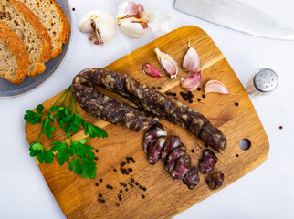 Appetizing Spanish cured pork sausage with garlic, peppercorns and a sprig of fresh parsley on a...