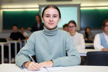 Young female student attentively listening to a lecture in a classroom
