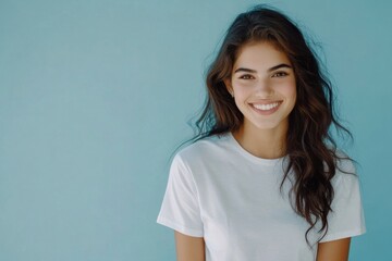 Fototapeta premium Portrait of a beautiful young woman in a white t-shirt against a blue background.
