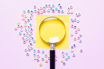 English letters scattered on pink background. Concept of thinking development, grammar. Magnifying glass placed on English letters.