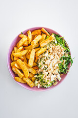 plate with half chips and half salad topped with tofu and almonds, healthy food vs junk food concept