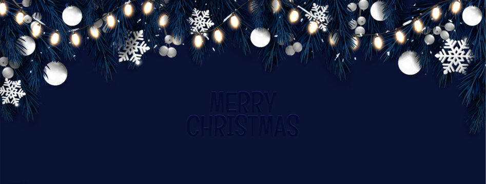 Christmas border with glowing string lights and dark blue evergreen branches. Night scene featuring white ornaments, silver snowflakes and greeting text. Noel holiday header or winter seasonal banner.