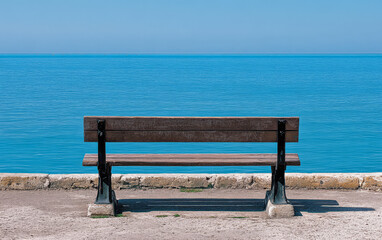 Serene wooden bench overlooking calm blue waters on a bright sunny day