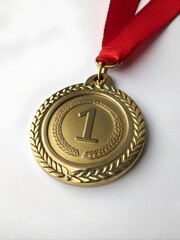 Gold medal with red ribbon displaying number one, cut out on white