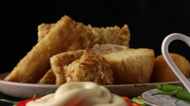 close up on dipping ubi goreng or fried sweet potato in the mayonnaise with a black background. famous Indonesian snack
