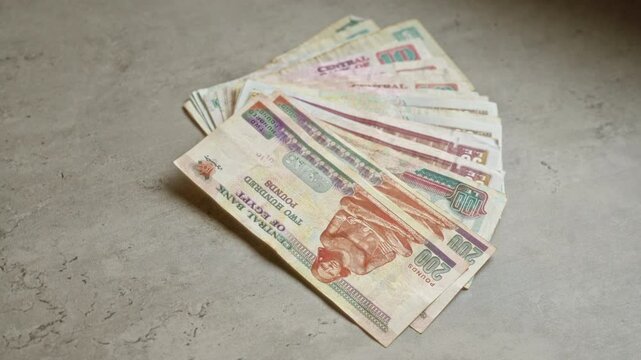 Egyptian banknotes on a concrete surface showcase various denominations of the egyptian pound, highlighting intricate designs in a financial context.