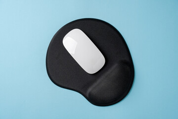 Top view of modern white mouse on black mousepad on blue table