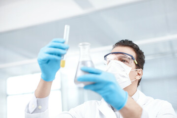 Man, scientist or face mask with vial or beaker for chemical experiment, test or exam at lab. Male...