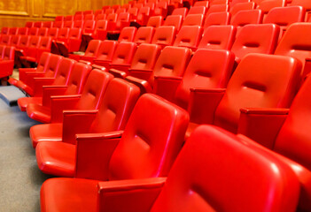A row of red chairs are empty in a large auditorium