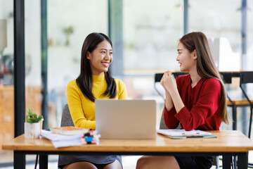 Obraz premium Shot of two businessasianwomen working together on digital tablet. Creative female executives meeting in an office using tablet pc and smiling. 