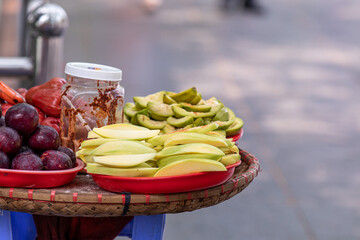 Slices of green mango covered with a spice on a table of the streets of Hanoi, Vietnam