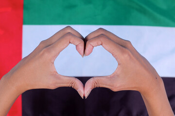 Fototapeta premium Close Up of Hands Showing Heart Sign With UAE National Flag Background