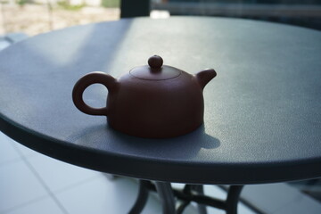 Small red Chinese teapot on the  round black table. Yixing clay teapot
