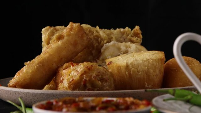 close up on dipping combro in the sambal with a black background. Combro is a typical Sundanese fried food. Comro is made from grated cassava which is shaped round or oval and filled with oncom
