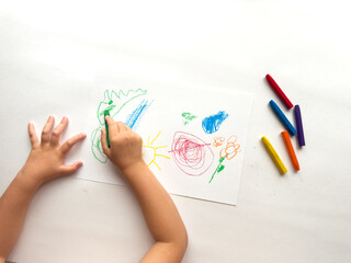 Child drawing colorful art with crayons on paper