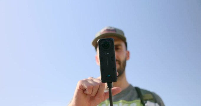 Low angle close-up of Insta360 x4 camera mounted on stick with man viewing menu