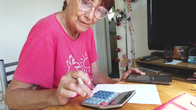 Senior lady close up shot woman with glasses calculates home office bills to pay
