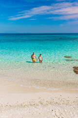 Obraz premium Sun-kissed couples stroll hand in hand along the sandy shores of Koh Munnork Island in Rayong