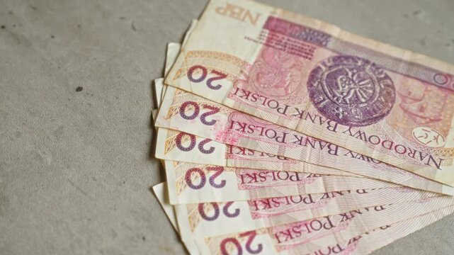 Polish zloty banknotes scattered on a concrete surface, showcasing the currency of poland with closeup details of the 20 pln notes.