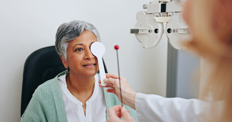Doctor, optometry and woman in exam for vision, hands and senior person with occluder or fixation stick in clinic. Ophthalmologist, test and patient with tools for health, cover and eye alignment