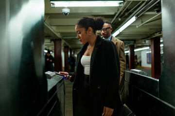Businesswoman using smart phone to enter subway station