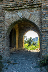 View of the mountain and tree through the arch. The church on the hill among bushes and trees is part of the Shio-Mgvime monastery.