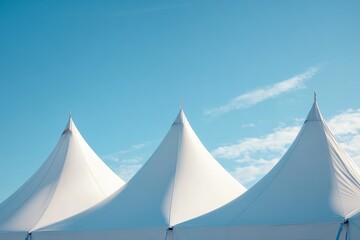 Three white tents with blue sky in the background