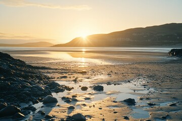 Obraz premium The sun is setting over the ocean, casting a warm glow on the rocky shore