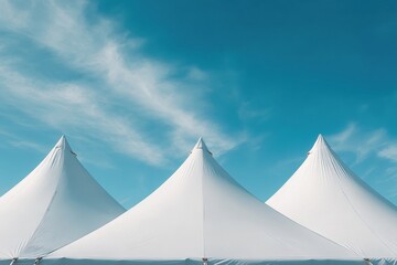 Three white tents with blue sky in the background