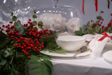 Beautiful table setting for Christmas or New Year dinner. Table decoration with red berries. Restaurant christmas decoration.