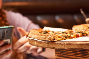 Close-up of pizza slices on a wooden stand in a cafe.    