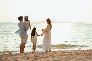 children, parents, parent, family, friends, kids, relaxed, relaxation, father, together. A family of four is standing on the beach. The family is enjoying a day at the beach.
