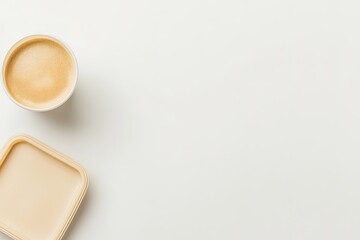 flat lay of reusable coffee cup and biodegradable lunch box arranged on clean white surface with soft shadows