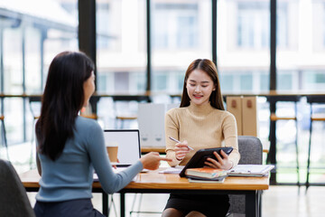 Two asian female creative agency casual meeting discussion working with laptop, analyze planning and financial statistics and investment market at office.
