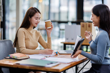 Two asian female creative agency casual meeting discussion working with laptop, analyze planning and financial statistics and investment market at office.
