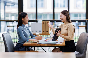 Two asian female creative agency casual meeting discussion working with laptop, analyze planning and financial statistics and investment market at office.
