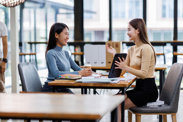 Two asian female creative agency casual meeting discussion working with laptop, analyze planning and financial statistics and investment market at office.
