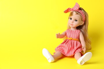 Beautiful doll in dress and headband on yellow background. Space for text