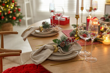 Christmas celebration. Festive table setting with dishware, glasses and decor in room