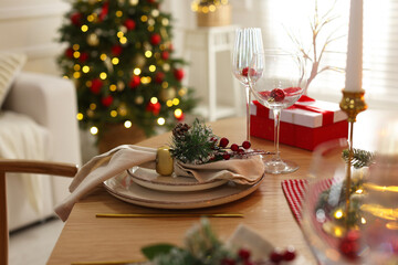 Christmas place setting with festive decor on wooden table in room