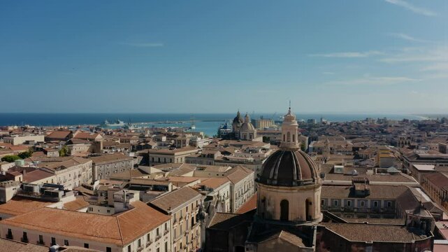 Cinematic orbit drone flight around San Michele Arcangelo ai Minoriti Cathedral in Catania with sea port in the background. Catania old town from above.